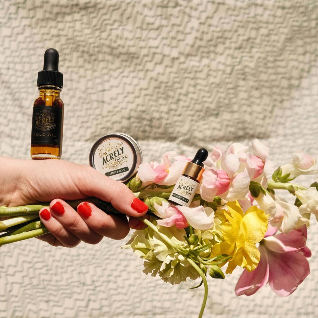 A woman holding a bouquet of flowers and a bottle of essential oils