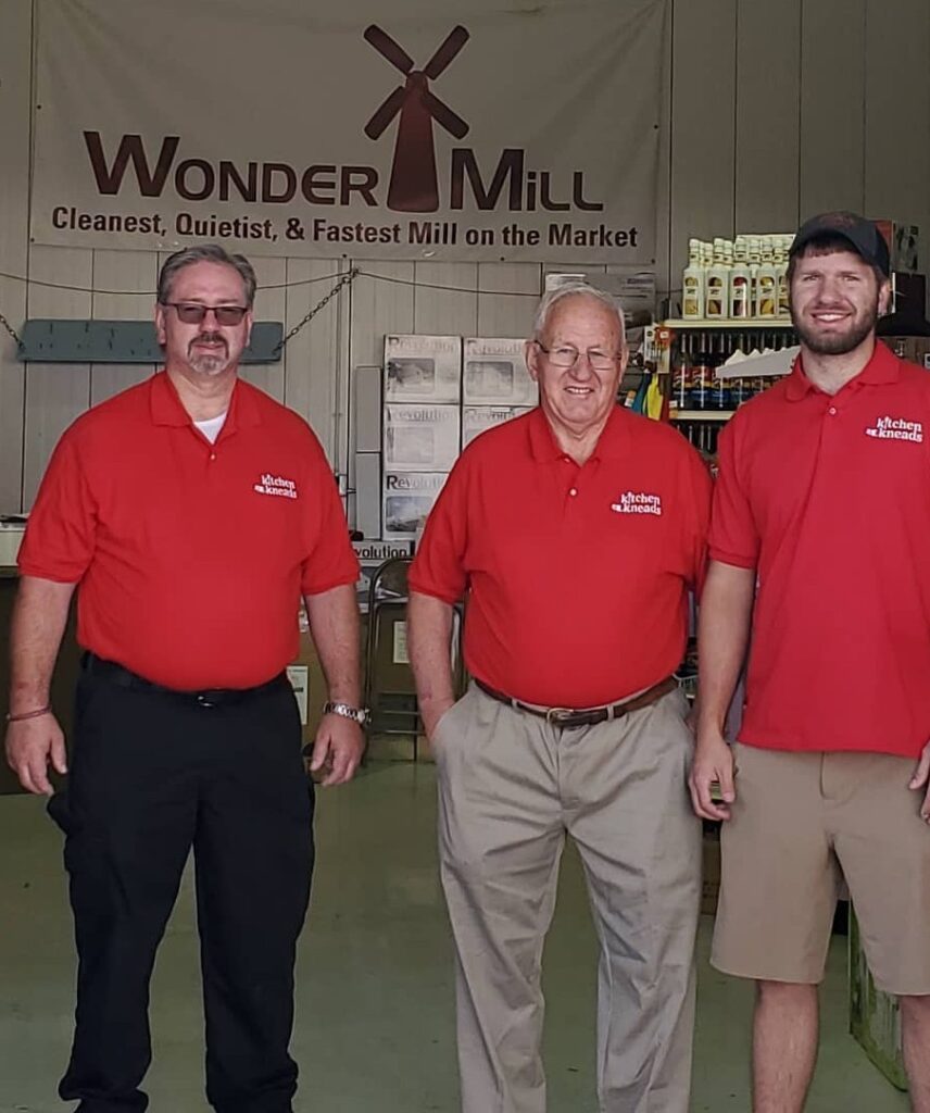 three people standing beneath a sign that reads Wonder Mill