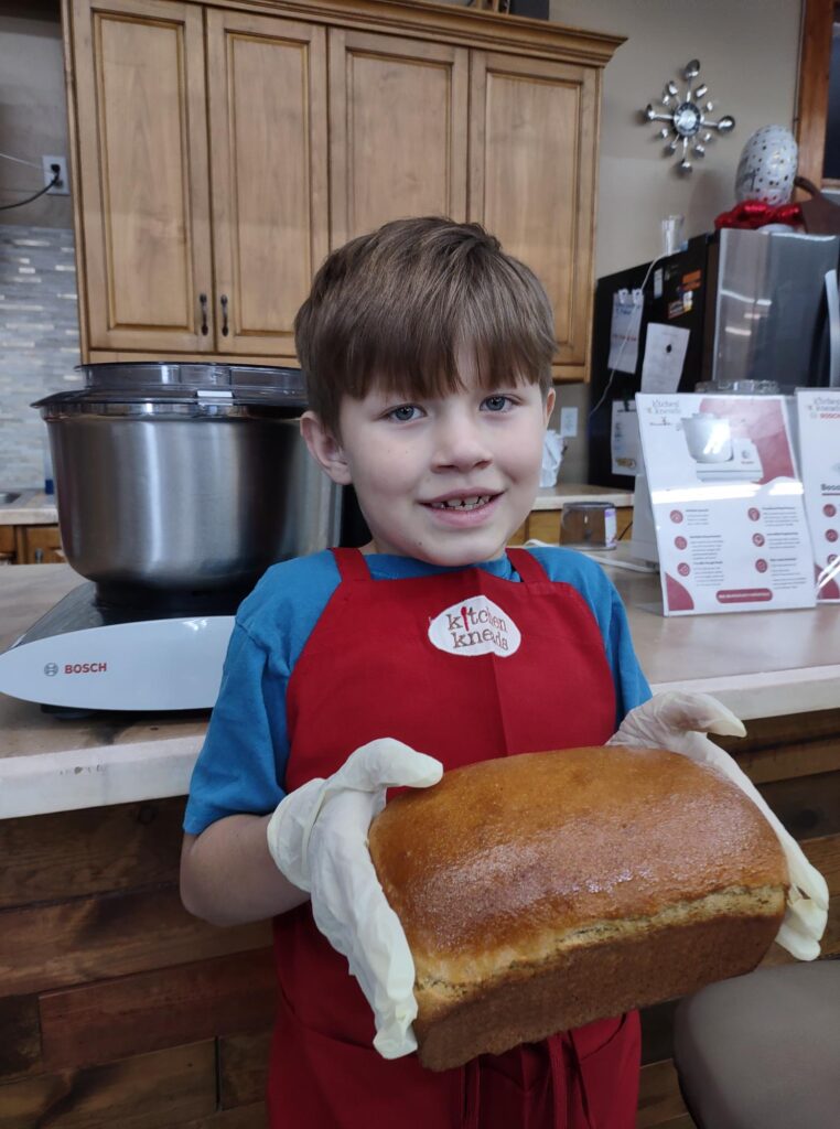 a young man holds a loaf of bread