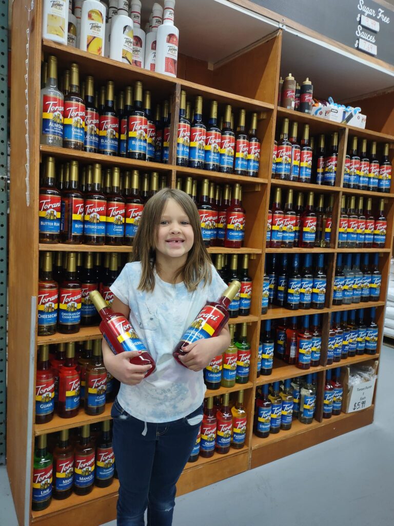 a young girl holds flavoring syrups