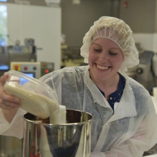 Aggie Chocolate Owner pouring a liquid into a machine