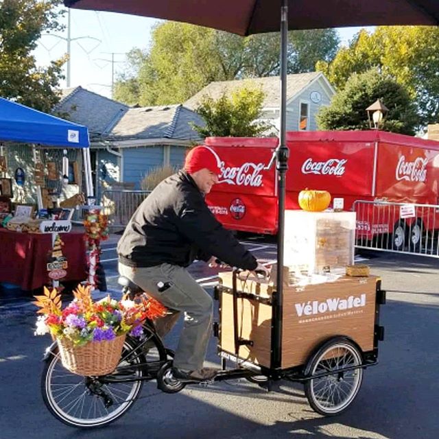 A man riding a bike with a cart on the back of it for transportation purposes