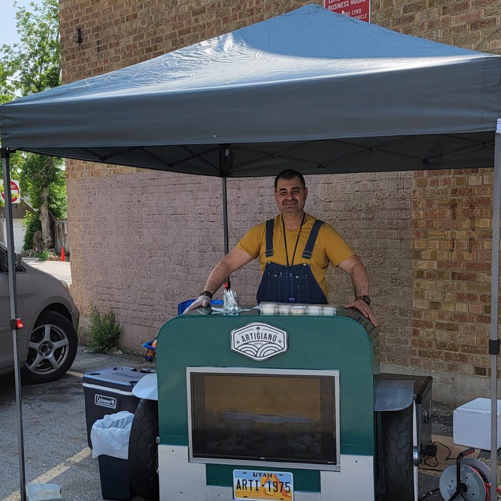 A man standing behind a food cart with green and white colors