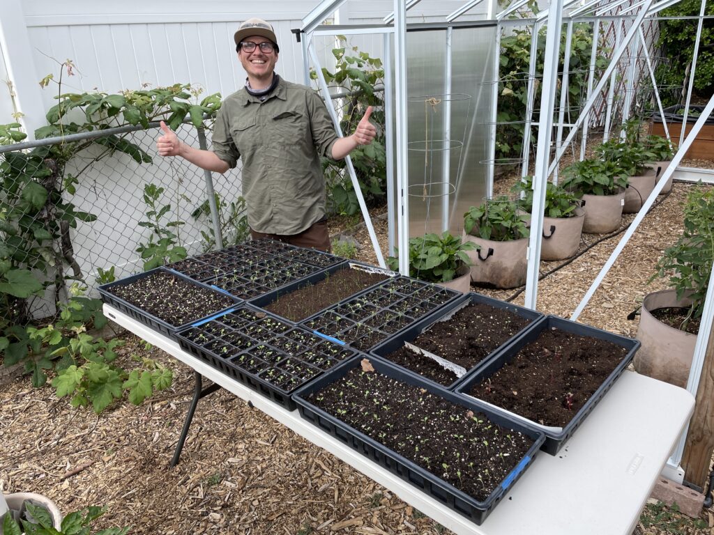 A man standing in front of a variety of green plants