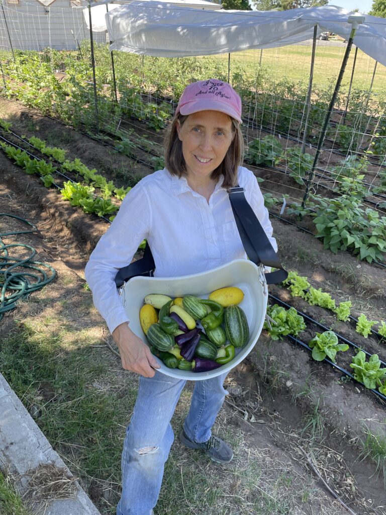 A girl holding a bowl of fresh vegetables in a garden