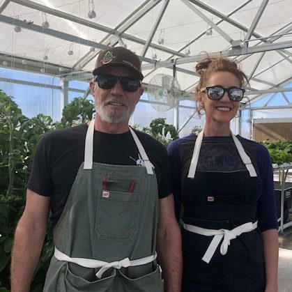 A man and a woman standing in a greenhouse