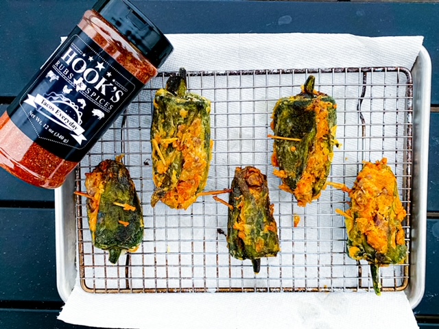 A tray with assorted dishes next to a bottle of hot sauce
