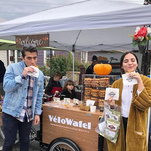 A man and a woman standing next to a food cart