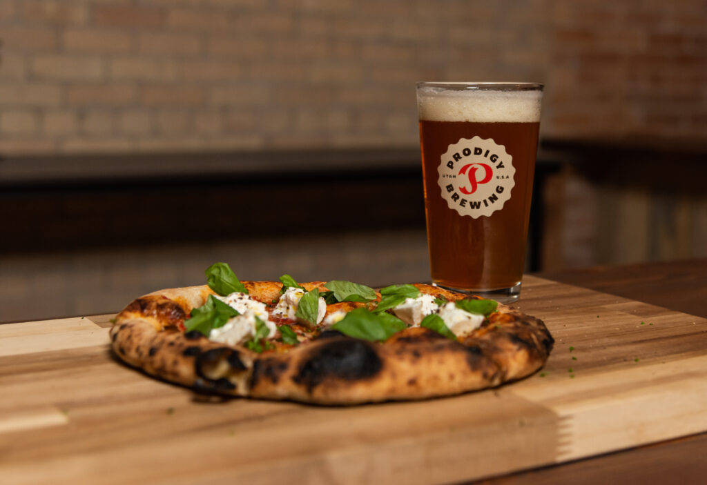 A delicious pizza on a wooden table beside a glass of beer