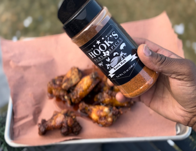 A person holding a jar of sauce over a plate of food
