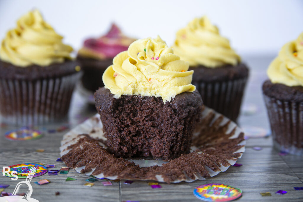 A chocolate cupcake with yellow frosting and sprinkles