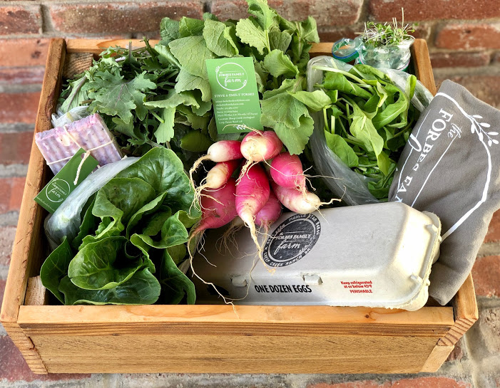 A wooden box filled with a variety of fresh vegetables