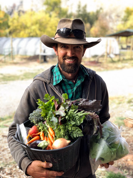 A man in a hat holding a basket of fresh vegetables