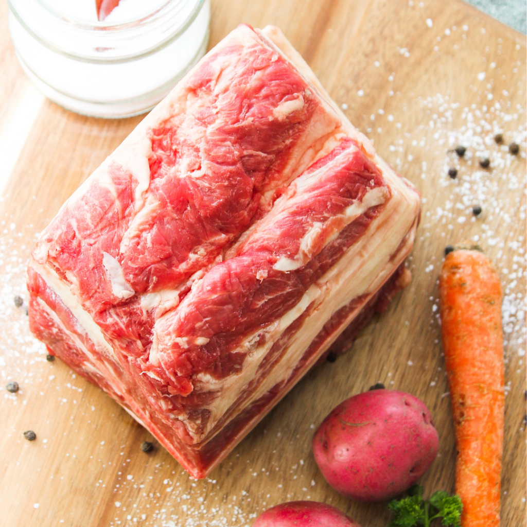 Cut of steak on cutting board with carrots and seasoning