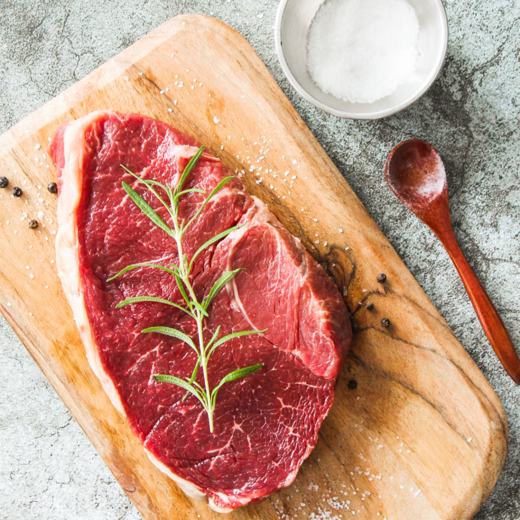 Cut of steak on cutting board with seasoning