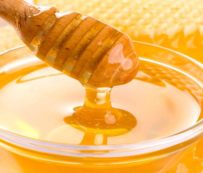 A honey dip being poured into a glass bowl