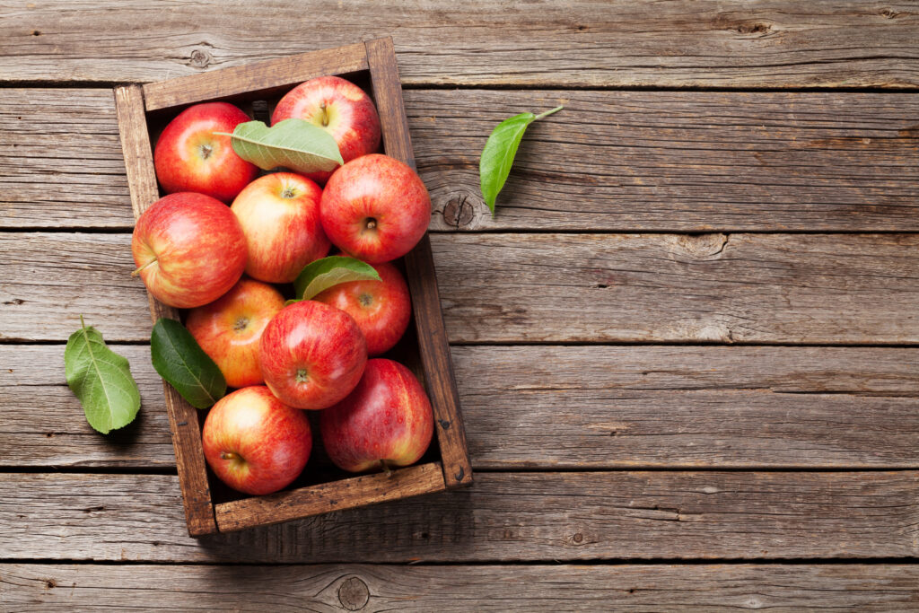 A wooden box filled with ripe red apples