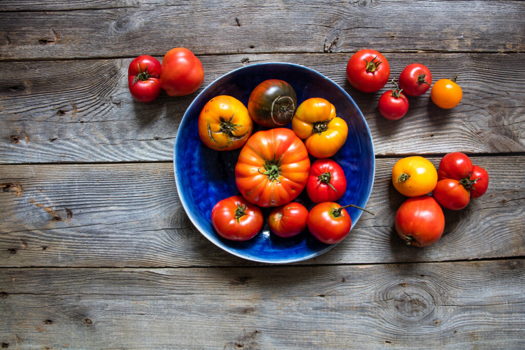 A blue bowl filled with ripe red and yellow tomatoes