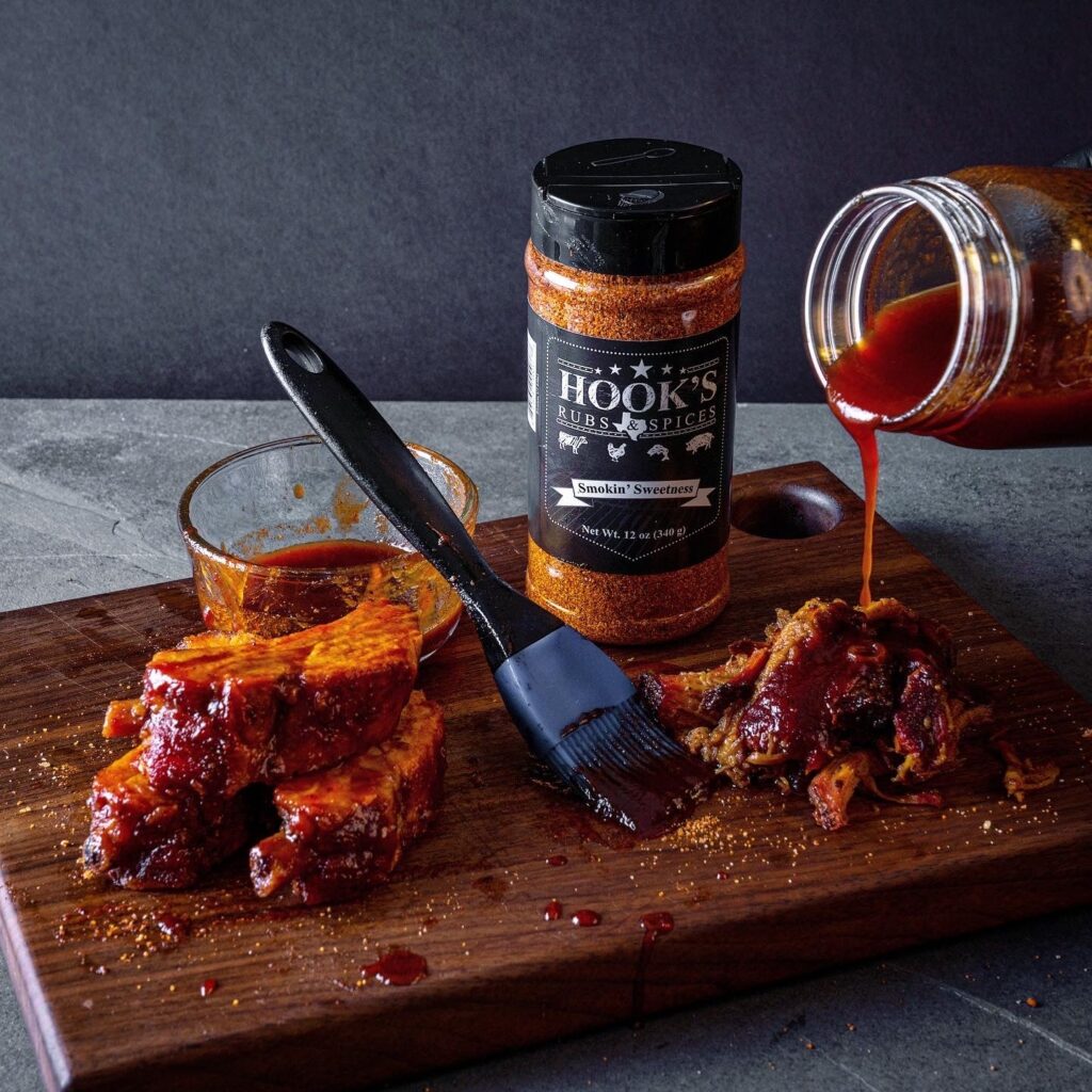 A wooden cutting board topped with ribs covered in BBQ sauce