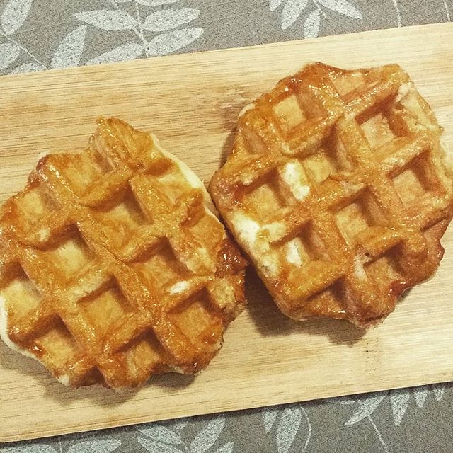 two waffles displayed on a wooden cutting board