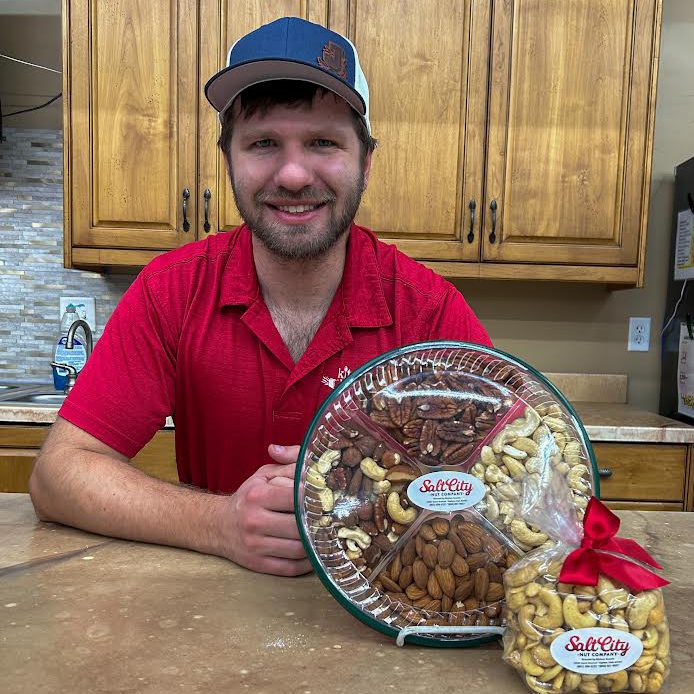 A man sitting at a kitchen counter holding a platter of nuts