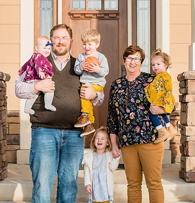 A family of four standing in front of a house