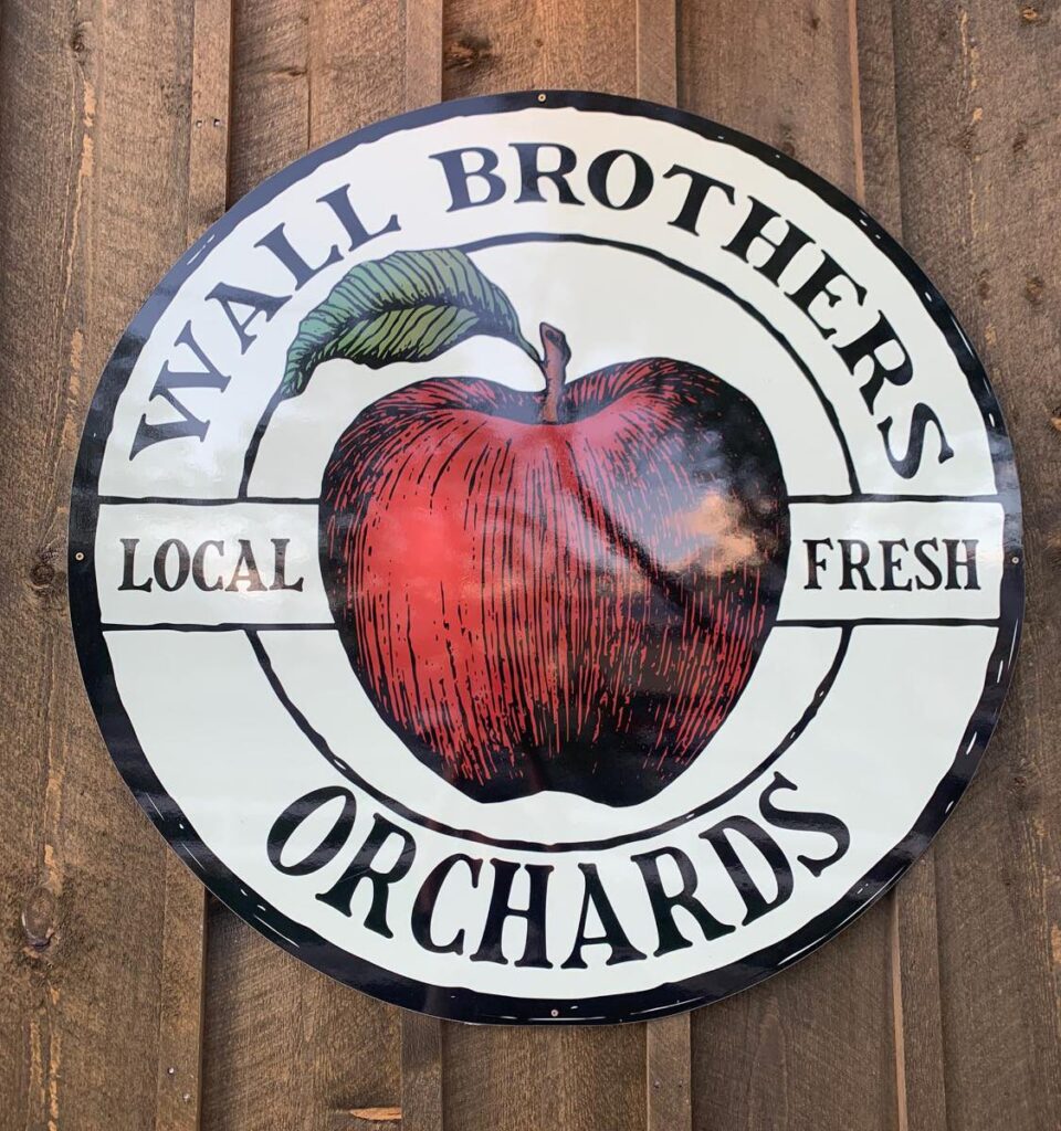 A sign on a wooden fence with the words "Wall Brothers Orchards" displayed prominently